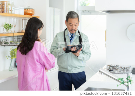 A real estate agent and a middle-aged woman doing maintenance in the kitchen A real estate agent and a middle-aged woman doing maintenance in the kitchen 131637481