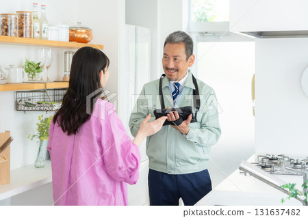 A real estate agent and a middle-aged woman doing maintenance in the kitchen 131637482