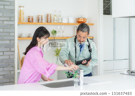 A real estate agent and a middle-aged woman doing maintenance in the kitchen A real estate agent and a middle-aged woman doing maintenance in the kitchen 131637483