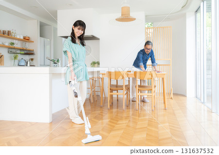 A middle-aged couple cleaning the living room 131637532