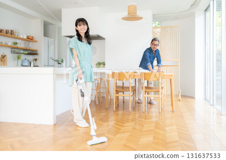 A middle-aged couple cleaning the living room 131637533