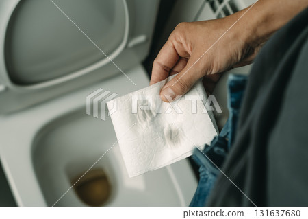 a man holding toilet paper after urinating 131637680