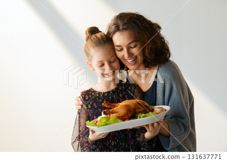 Woman and child holding a roast turkey together 131637771