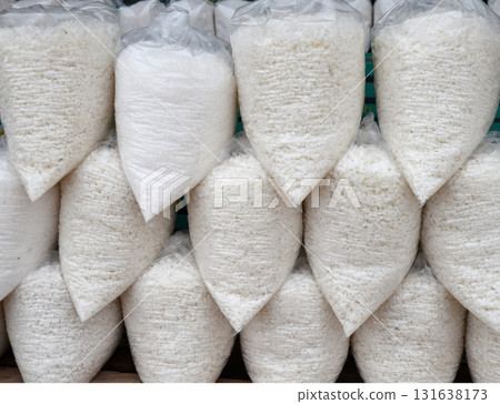 Large pellets of white raw salt packed in clear plastic bags stacked on top of each other. 131638173