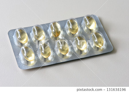Top view of a pill pack full of yellow gel capsules medicine on white background 131638196
