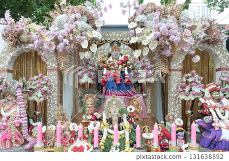 The statue of Sri Maha Lakshmi Devi or Ambabai is a Hindu goddess of wealth, prosperity and fortune with Other gods on a decorated platform with candles and an elaborate pink and white floral The statue of Sri Maha Lakshmi Devi or Ambabai is a Hindu goddess of wealth, prosperity and fortune with Other gods on a decorated platform with candles and an elaborate pink and white floral 131638892