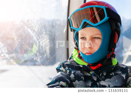 Portrait of cute confident pensive little kid boy enjoy having fun sit ski lift gondola at alpine mountain skiing resort on bright winter day. Toddler beginner skier rest of training in ski school 131639131