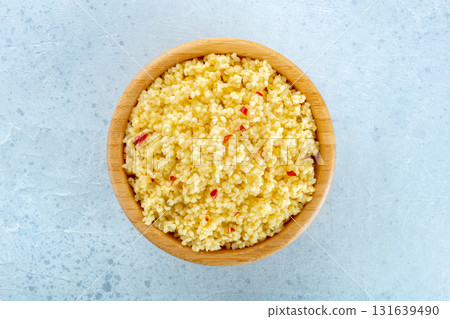 Cooked millet, ancient African grain, in a wooden bowl on a blue background Cooked millet, ancient African grain, in a wooden bowl on a blue background 131639490