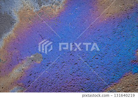 Abstract colorful background of iridescent oil texture on wet asphalt surface with vivid blue and purple shades. Concept of liquid pattern, creative backdrop, vibrant street texture. Copy space 131640219