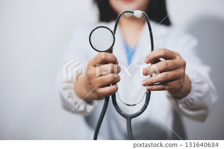A young male doctor holding an stethoscope A young male doctor holding an stethoscope 131640684