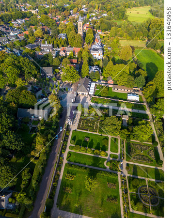 Aerial view of picturesque town with tall steeple church, formal garden, tree lined streets, and historic buildings showcasing harmony between architecture and natural design. 131640958