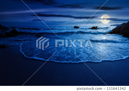 calm sea landscape with wave rolling on sandy beach with boulders at night. scenic seascape in full moon light. relax and summer vacation on the shore concept 131641342