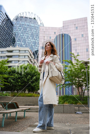 Woman in trench coat standing city park 131641531