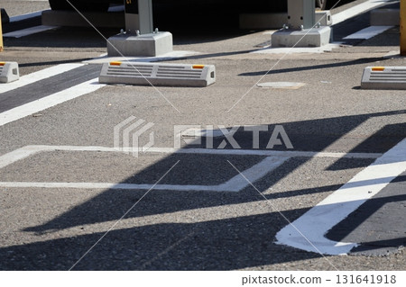 A view of a parking lot with asphalt, white lines and bollards 131641918