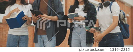 Happy students walking together on university campus, chatting and laughing outdoors after classes 131642215