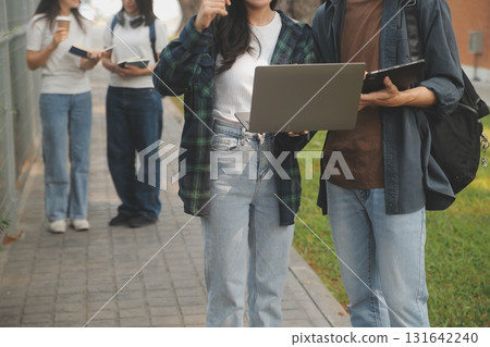Happy students walking together on university campus, chatting and laughing outdoors after classes Happy students walking together on university campus, chatting and laughing outdoors after classes 131642240