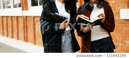 Happy students walking together on university campus, chatting and laughing outdoors after classes Happy students walking together on university campus, chatting and laughing outdoors after classes 131642299