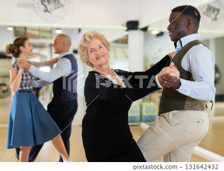 Man and elderly woman performing jazz dance in dancing room Man and elderly woman performing jazz dance in dancing room 131642432