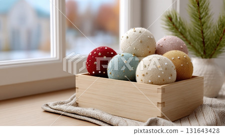 A cozy arrangement of festive handmade baubles in a wooden box by the window 131643428