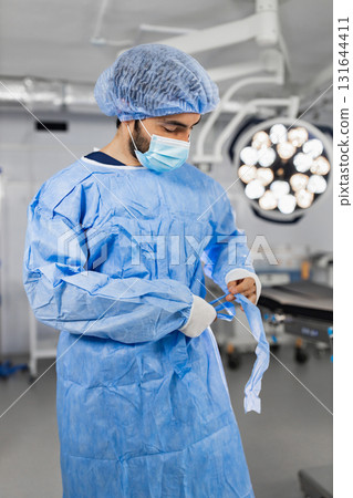 A surgeon in a surgical gown and mask prepares for an operation in a modern operating room. 131644411