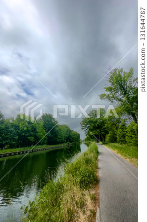 A Serene and Winding Waterside Path Surrounded by Lush Greenery and Idyllic Landscape A Serene and Winding Waterside Path Surrounded by Lush Greenery and Idyllic Landscape 131644787