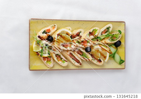 Rolls vegetables olives Delicious rolls of fried zucchini slices and feta cheese with rucola, served with olive oil and pieces of bell peppers 131645218