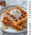Stack of golden waffles topped with whipped cream and maple syrup, served on a white plate. A sweet and cozy breakfast perfect for holidays, brunch, or weekend mornings 131645655