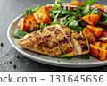 Grilled chicken breast served with roasted sweet potatoes and a fresh arugula salad. Perfect for healthy eating, diet menus, fitness blogs, or Thanksgiving meal ideas. 131645656