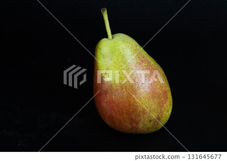 Single Green and Red Corella Pear Isolated on Black. Natural Sweet Snack. 131645677