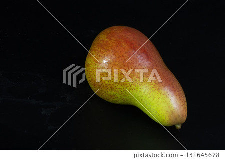 Single Green and Red Corella Pear Isolated on Black. Natural Sweet Snack. 131645678