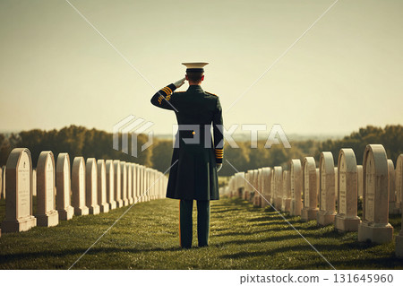A military officer salutes in a cemetery among tombstones. White tombstones and green grass. 131645960