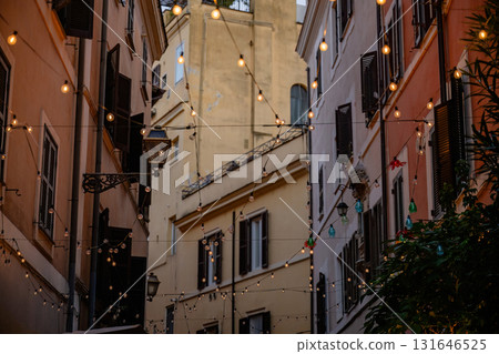 String lights hanging above narrow European street with historic buildings at dusk in Rome 131646525