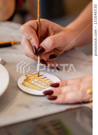 Female hand painting small round canvas with fine brush and detailed design Female hand painting small round canvas with fine brush and detailed design 131646530