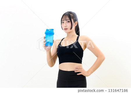 一位正在訓練的酷酷女人，手裡拿著蛋白搖瓶。肌肉訓練女孩。白色背景 131647186