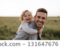 Joyful child laughing on parent back in vast open green field 131647676