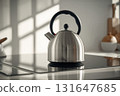 Stainless steel kettle glowing warmly in bright daylight within minimal modern kitchen 131647685