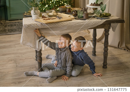 Funny naughty boys are sitting under the Christmas table, waiting for a holiday and miracles 131647775