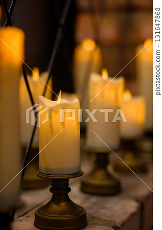 Row of warm yellow LED candles in candle holders for event decor in the dark 131647868