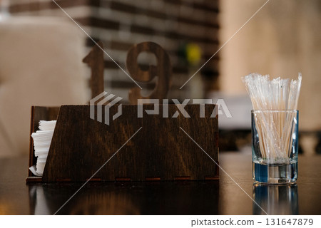 A wooden napkin holder with toothpicks in a glass on a table in a cafe 131647879
