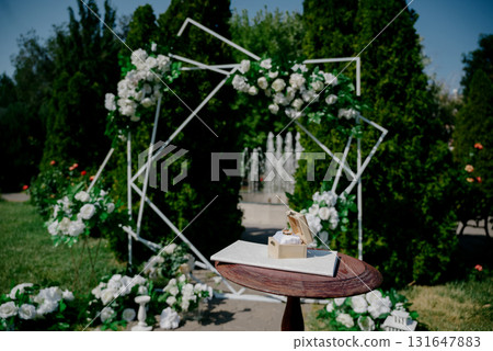 Wedding rings in a wooden box on a table in front of a arch 131647883