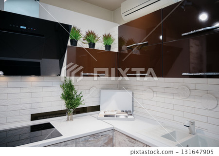 A trendy kitchen with white countertops, an induction hob, and spotlights 131647905