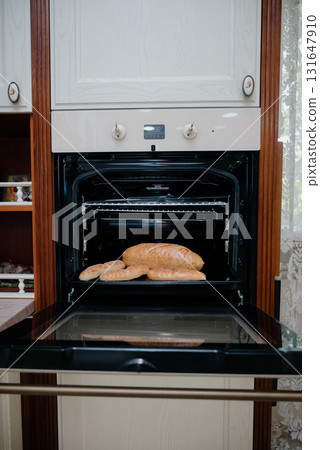 Ruddy freshly baked bread on a baking sheet in a black electric oven Ruddy freshly baked bread on a baking sheet in a black electric oven 131647910