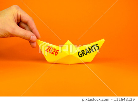 2026 Grants symbol. Concept words 2026 Grants on beautiful yellow paper boat. Beautiful orange paper background. Businessman's hand. Business and 2026 grants concept. Copy space. 2026 Grants symbol. Concept words 2026 Grants on beautiful yellow paper boat. Beautiful orange paper background. Businessman's hand. Business and 2026 grants concept. Copy space. 131648129