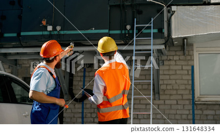 Construction engineers inspecting ventilation system outdoors Construction engineers inspecting ventilation system outdoors 131648334