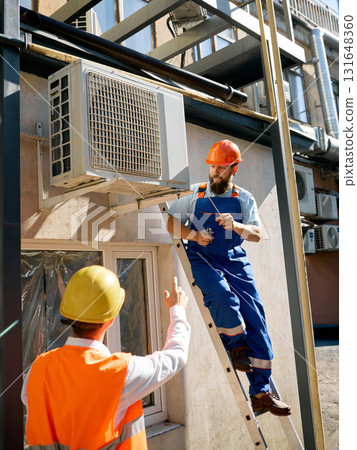 Engineers discussing air conditioner installation on site Engineers discussing air conditioner installation on site 131648360