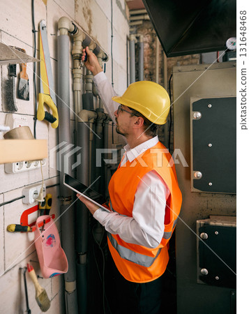 Engineer inspecting heating system with tablet control Engineer inspecting heating system with tablet control 131648468
