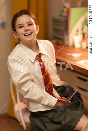 Happy schoolgirl sitting at desk in cozy room Happy schoolgirl sitting at desk in cozy room 131648725