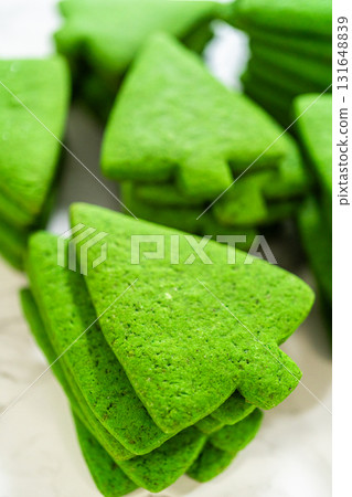 A stack of plain green Christmas tree cookies, emphasizing their vibrant green color and smooth texture. 131648839