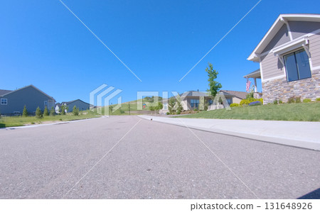 Ground-level image of a newly developed suburban area featuring landscaped front yards and clear skies. The residential road curves slightly, enhancing the sense of depth and structure. Ground-level image of a newly developed suburban area featuring landscaped front yards and clear skies. The residential road curves slightly, enhancing the sense of depth and structure. 131648926