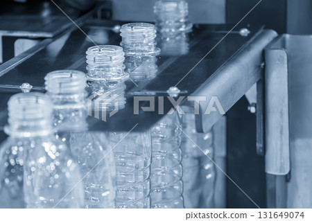 The  empty drinking water bottles  on the conveyor belt from blow mold machine in the light blue scene 131649074